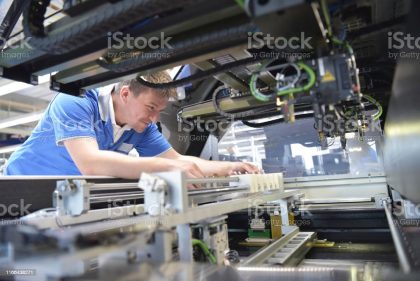 engineer working on a machine for assembly and production of semiconductor boards in an industrial plant